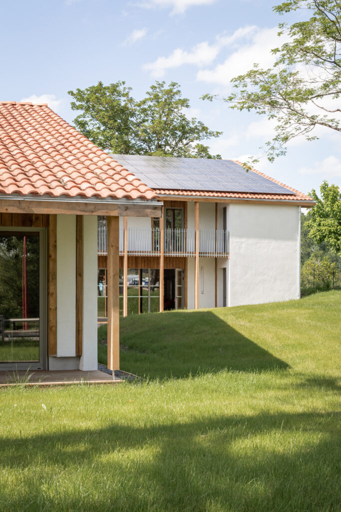 Volumes de la Maison de Santé AMIKUZE avec toiture traditionnelle et panneaux photovoltaïques.