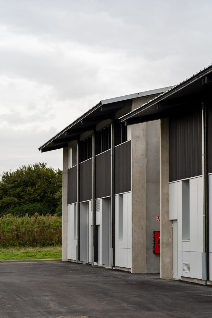 Façade contemporaine en béton brut et bardage métallique de la pépinière d'entreprises.