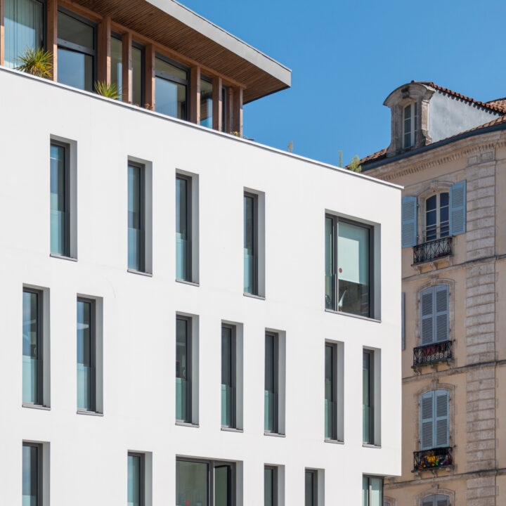Architecture contemporaine du Pôle santé à Bayonne avec façades enduites blanches et attique en bois.