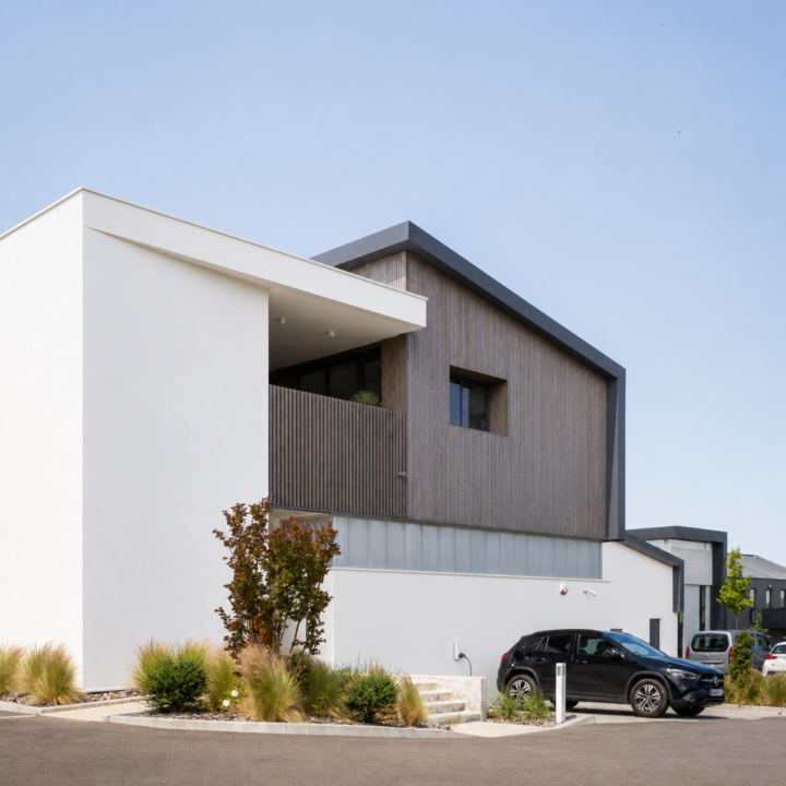 Façade contemporaine de l'atelier de menuiserie Castel à Villefranque avec bardage bois vertical et volumes géométriques.