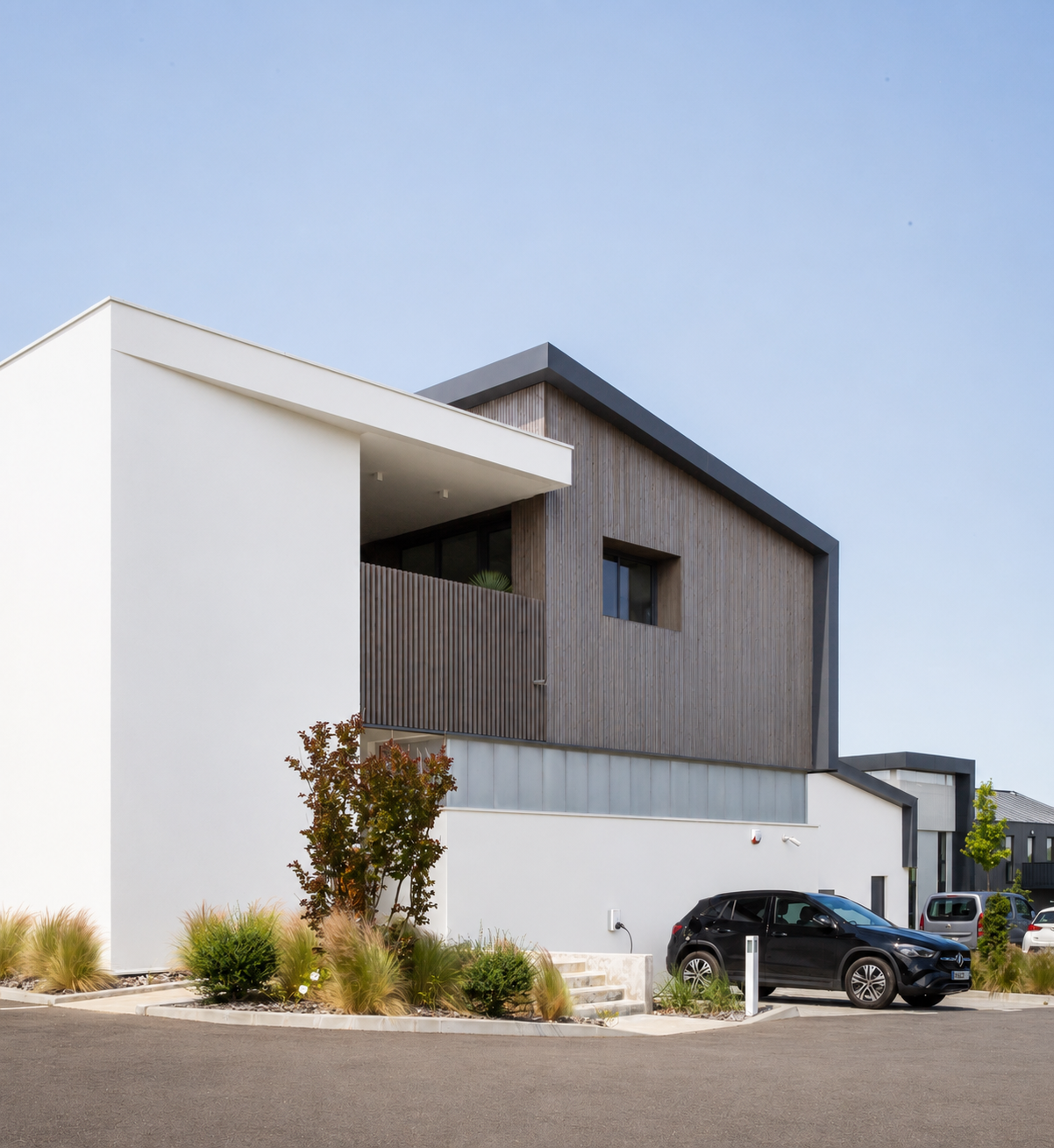 Façade contemporaine de l'atelier de menuiserie Castel à Villefranque avec bardage bois vertical et volumes géométriques.