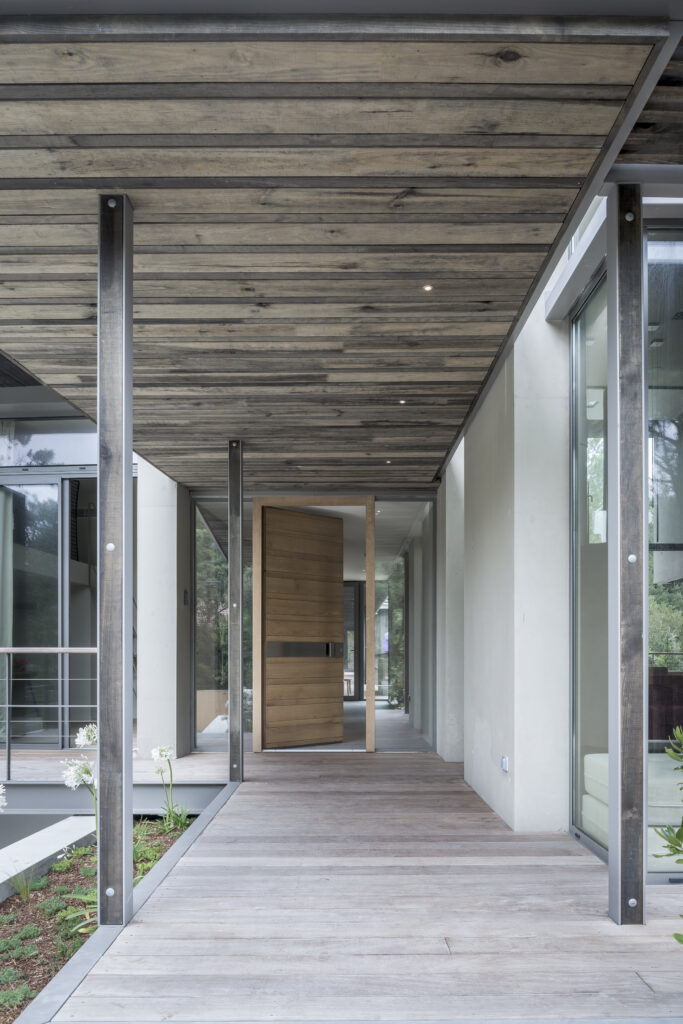 Galerie extérieure d'une villa d'architecte intégrée à la forêt.