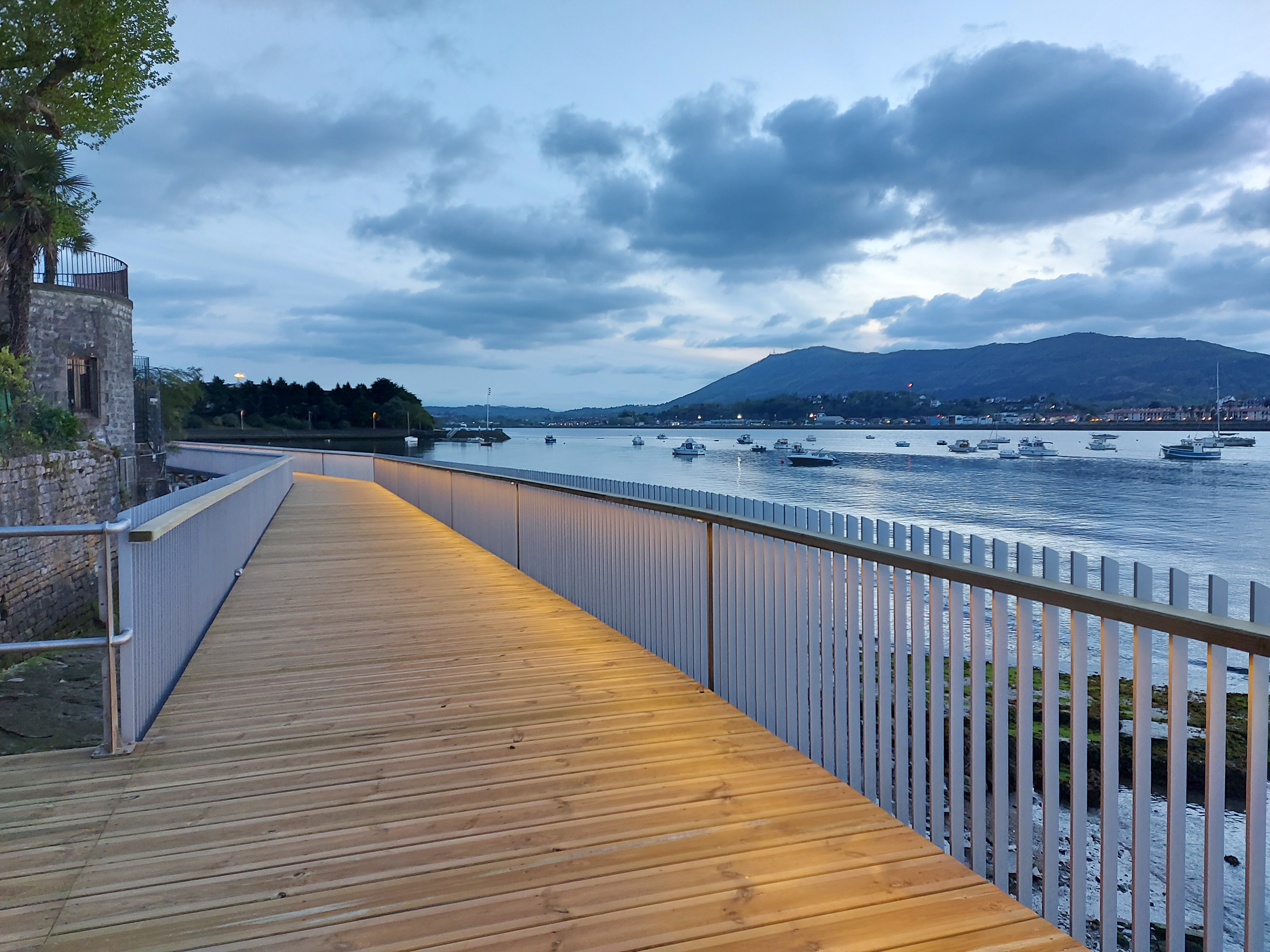 Passerelle Caneta illuminée au crépuscule, reflet doré dans l'eau calme de la baie d'Hendaye.