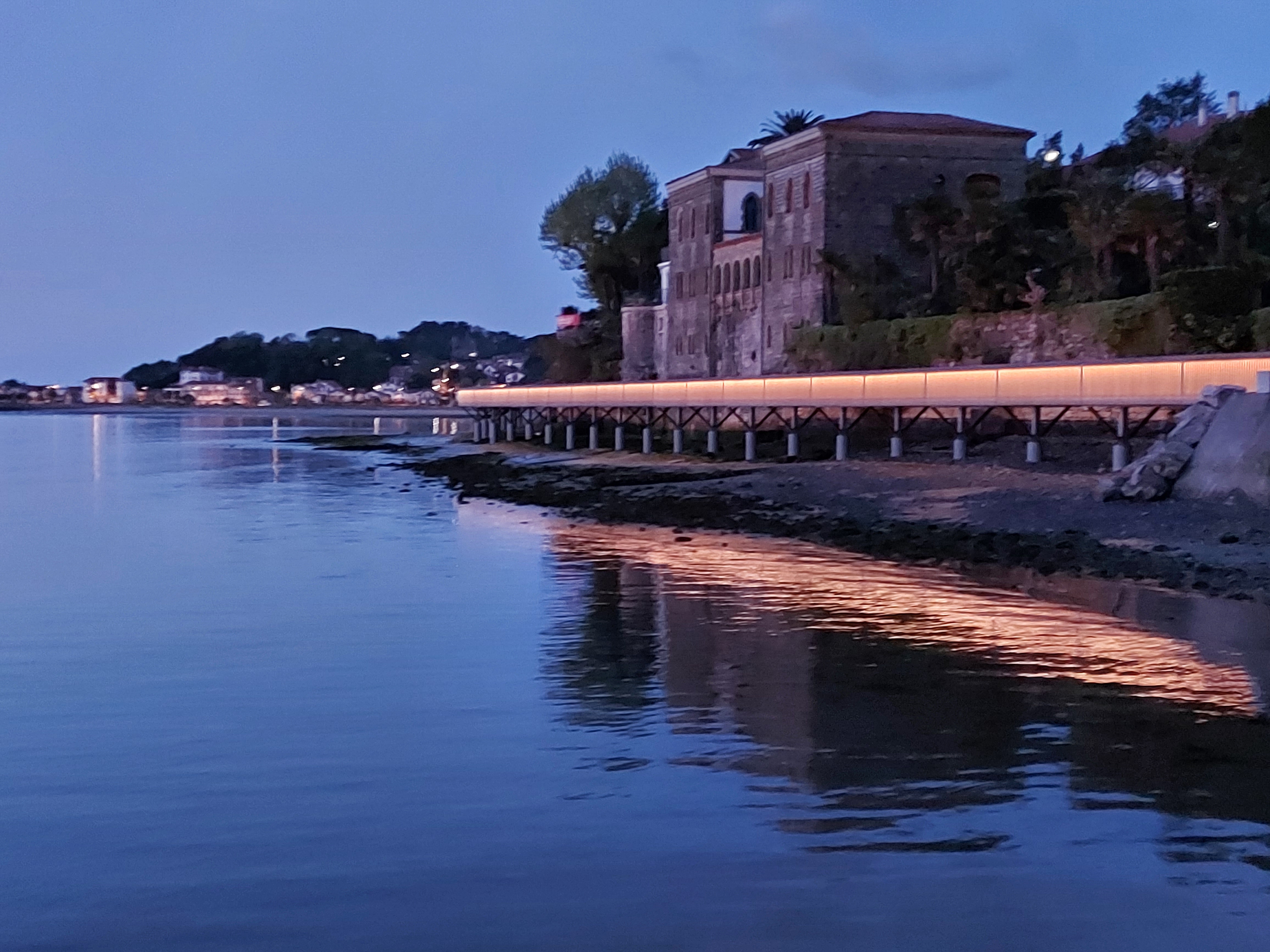 Passerelle Caneta illuminée au crépuscule, reflet doré dans l'eau calme de la baie d'Hendaye.