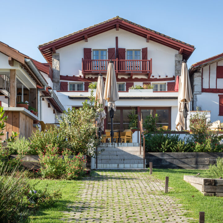 Terrasse de l'extension de l'Hôtel Oppoca avec mobilier extérieur jaune, parasols et escalier en pierre vers le jardin.