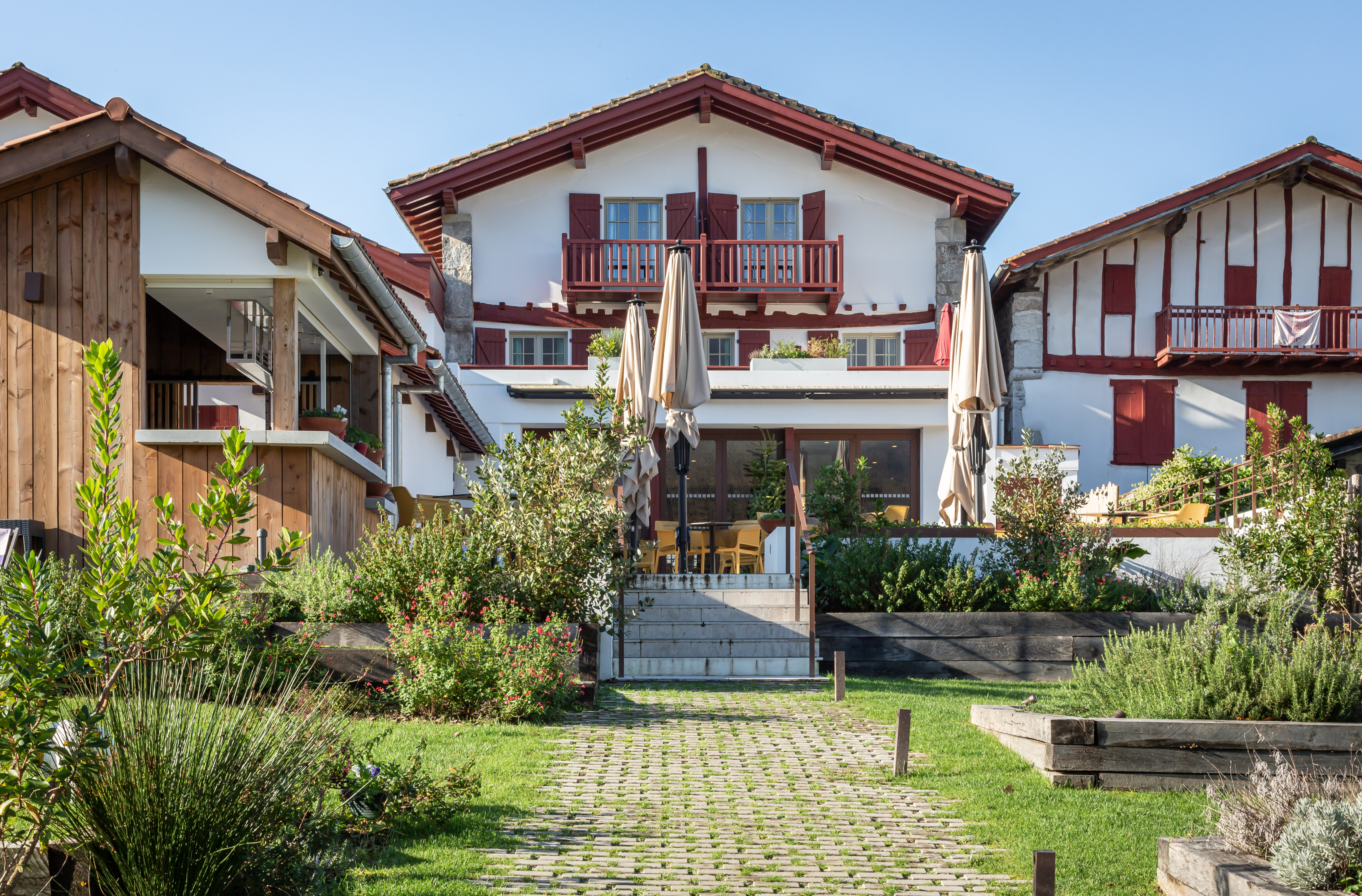Terrasse de l'extension de l'Hôtel Oppoca avec mobilier extérieur jaune, parasols et escalier en pierre vers le jardin.