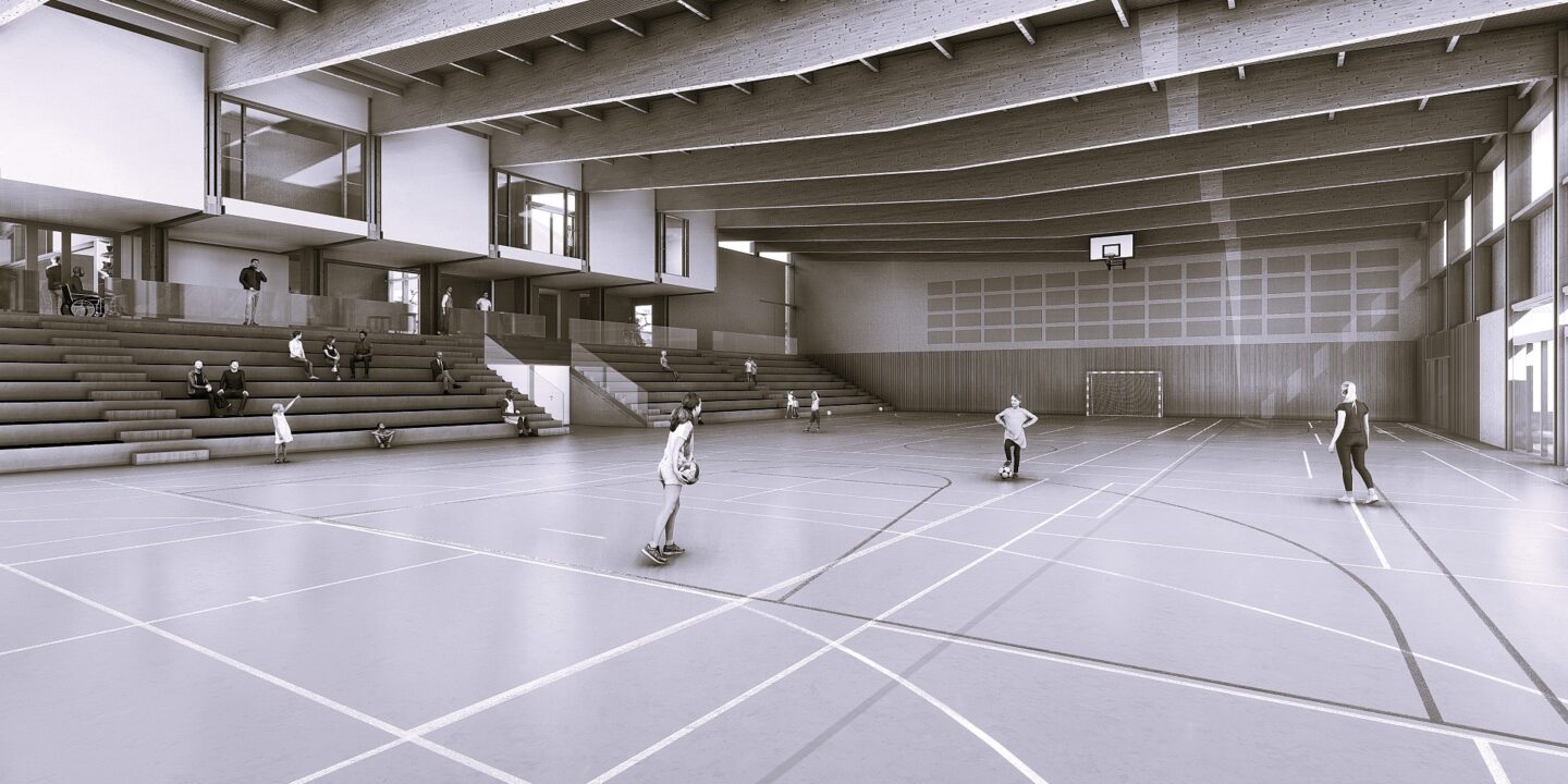 Vue intérieure de la salle omnisport de Baïgorry, charpente bois apparente, gradins et terrain de handball éclairés naturellement.