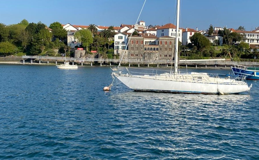 Voilier ancré face à la passerelle Caneta et aux maisons anciennes du front de mer d'Hendaye.