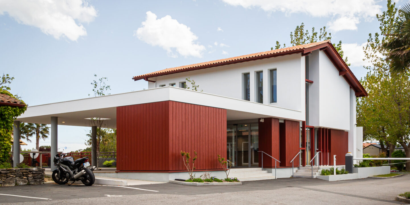 • Vue extérieure du nouveau bâtiment d’accueil du Camping Oyam à Bidart, associant architecture contemporaine et codes architecturaux basques.